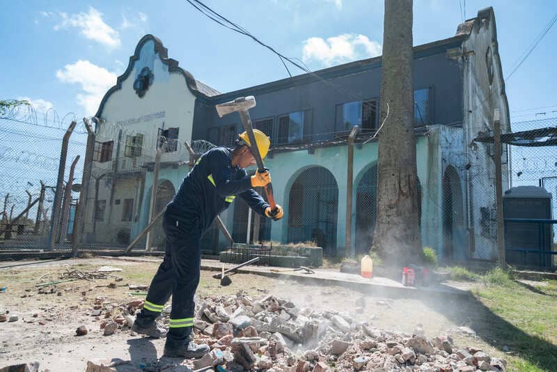Joven con un mazo rompiendo piso de hormigón